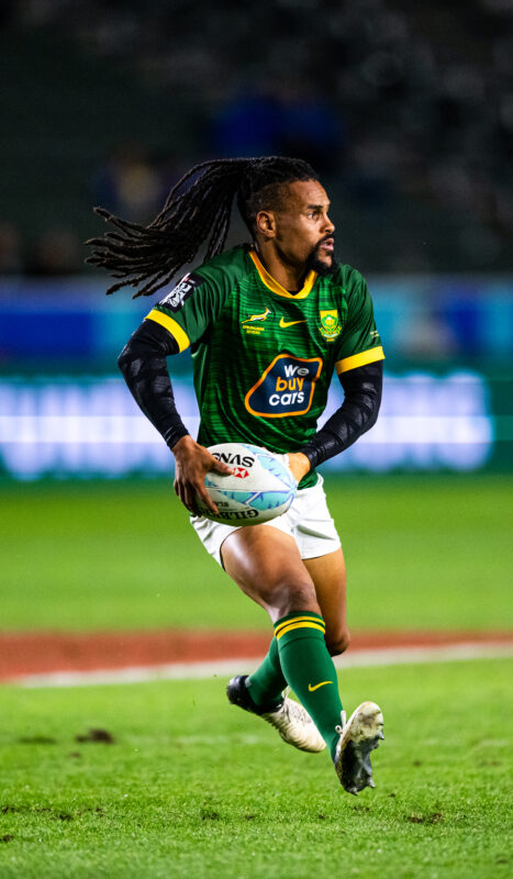 2024 HSBC SVN'S Rugby Tournament in Los Angeles at Dignity Health Sports Park. South Africa Rugby professional rugby player sports action photography. High-impact commercial sports imaging for team branding. Rugby player sprinting with ball, stiff-arming defender. Fast shutter speed sports photography capturing breakaway speed.