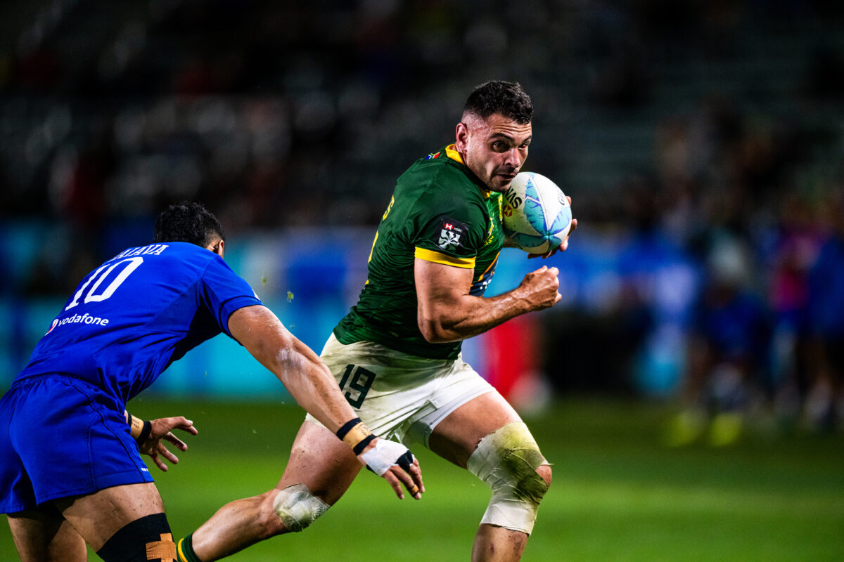 2024 HSBC SVN'S Rugby Tournament in Los Angeles at Dignity Health Sports Park. South Africa Rugby professional rugby player sports action photography. High-impact commercial sports imaging for team branding. Rugby player sprinting with ball, stiff-arming defender. Fast shutter speed sports photography capturing breakaway speed.