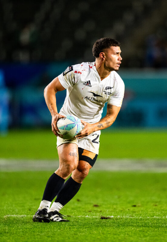 2024 HSBC SVN'S Rugby Tournament in Los Angeles at Dignity Health Sports Park. New Zealand All Blacks professional rugby player sports action photography. High-impact commercial sports imaging for team branding. Rugby player sprinting with ball, stiff-arming defender. Fast shutter speed sports photography capturing breakaway speed.