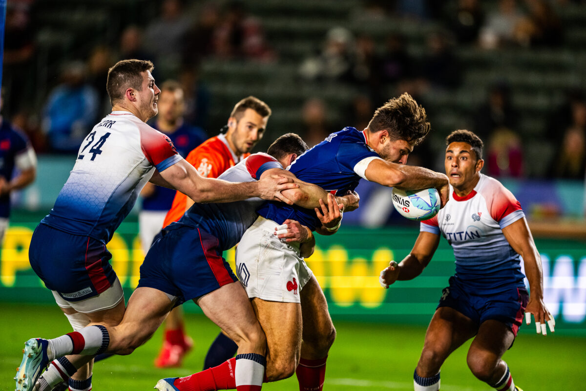 2024 HSBC SVN'S Rugby Tournament in Los Angeles at Dignity Health Sports Park. France Rugby professional rugby player sports action photography. High-impact commercial sports imaging for team branding. Rugby player sprinting with ball, stiff-arming defender. Fast shutter speed sports photography capturing breakaway speed.