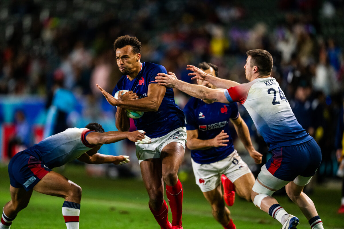 2024 HSBC SVN'S Rugby Tournament in Los Angeles at Dignity Health Sports Park. France Rugby professional rugby player sports action photography. High-impact commercial sports imaging for team branding. Rugby player sprinting with ball, stiff-arming defender. Fast shutter speed sports photography capturing breakaway speed.